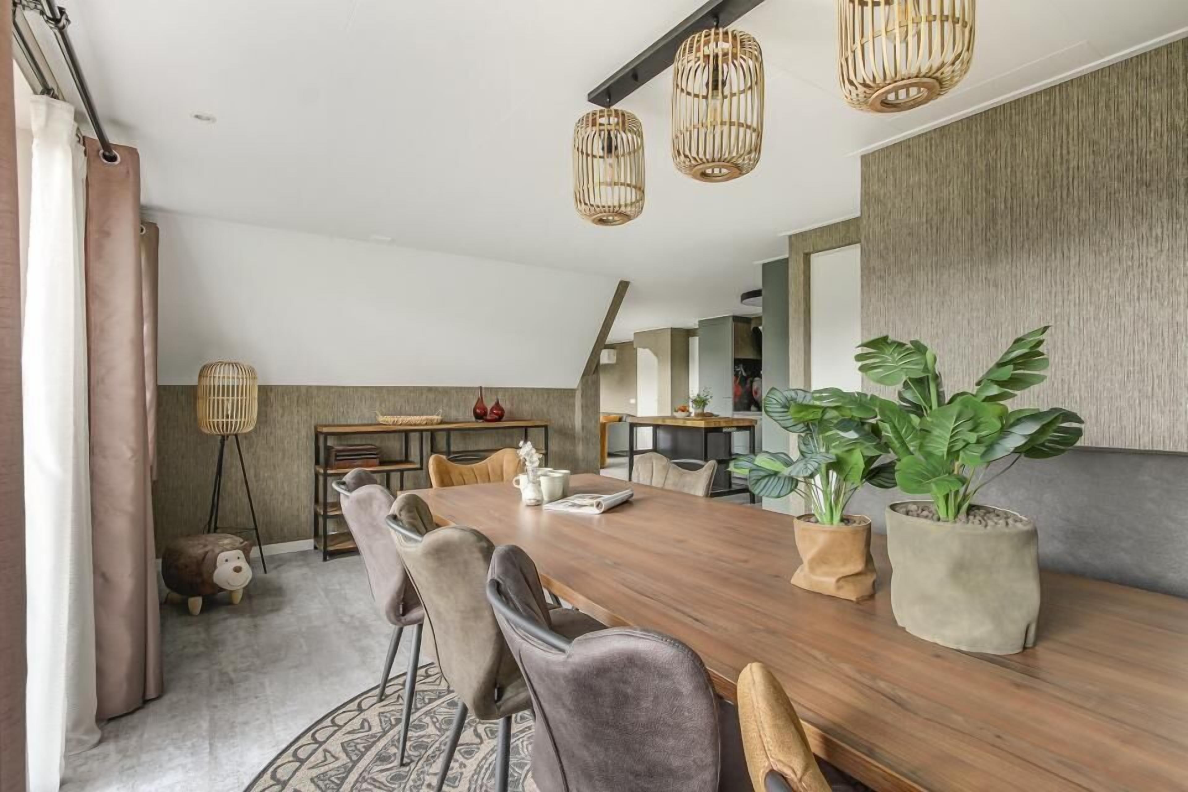A modern dining area with a wooden table, grey upholstered chairs, and hanging wicker lamps.