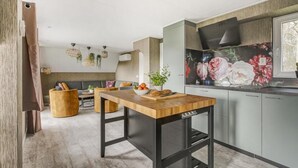 Une cuisine moderne avec une table en bois, des armoires grises et une fresque murale à motifs floraux.