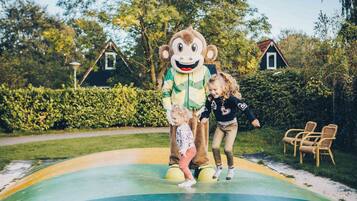 A person in a monkey costume standing on a colorful platform with a child.