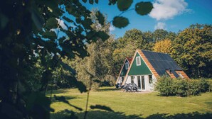 Une maison dotée d’un toit végétalisé et de panneaux solaires, entourée d’arbres et d’herbe.