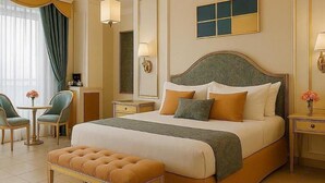Ein geräumiges Hotelzimmer mit einem großen Bett, einer Sitzecke mit Sesseln, einem Schreibtisch und einem Spiegel.