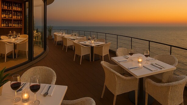 Ein Restaurant mit Tischen und Stühlen auf einer Terrasse mit Meerblick und Sonnenuntergang.
