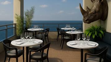 Una terrazza con tavoli rotondi, sedie e una scultura raffigurante la testa di un rinoceronte.