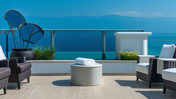 Una terraza en la azotea con mobiliario de mimbre, un otomano blanco y vista al mar.