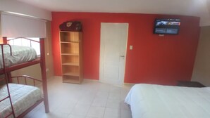 Ein Schlafsaalzimmer mit Etagenbetten, einem Schrank, einem Fernseher und einer Tür.