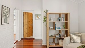 A hallway with a wooden door, a bookshelf, and a sofa. - Light-Filled North Perth Stay | Walk to Cafes | Stylish & Central (North Perth)