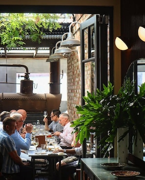 Um restaurante com mesas ao ar livre, uma parede de tijolos e um grande fogão industrial.