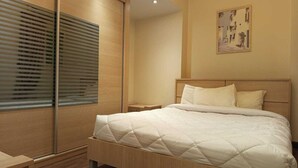 Ein Schlafzimmer mit einem großen Bett, einem Holzkopfende und einem Fenster mit Jalousien.