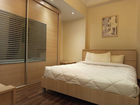 Un dormitorio con una cama grande, cabecera de madera y una ventana con persianas.
