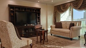Ein Wohnzimmer mit einem großen Flachbildfernseher, einem Sofa und einem Sessel.
