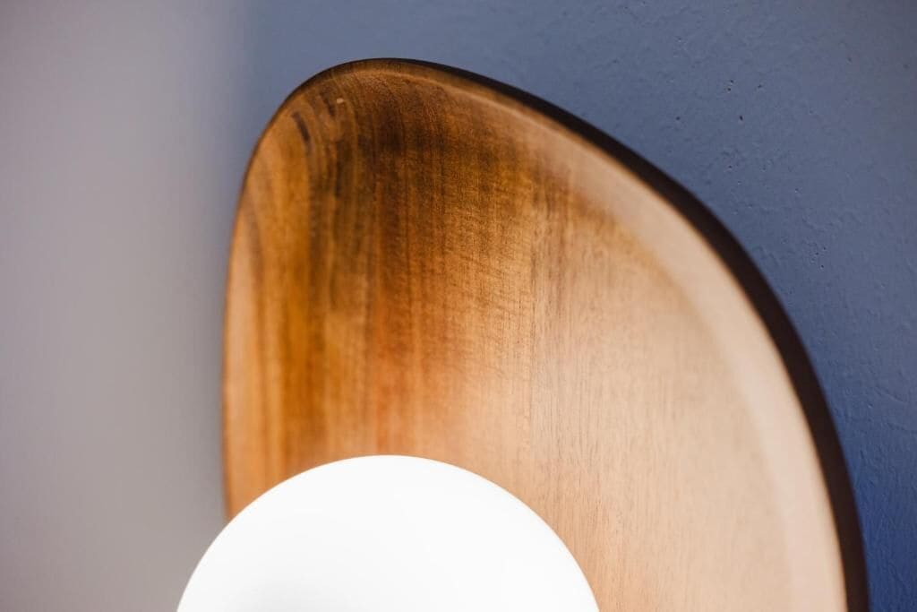Un objet en bois, fixé au mur, doté d’une lumière circulaire blanche.