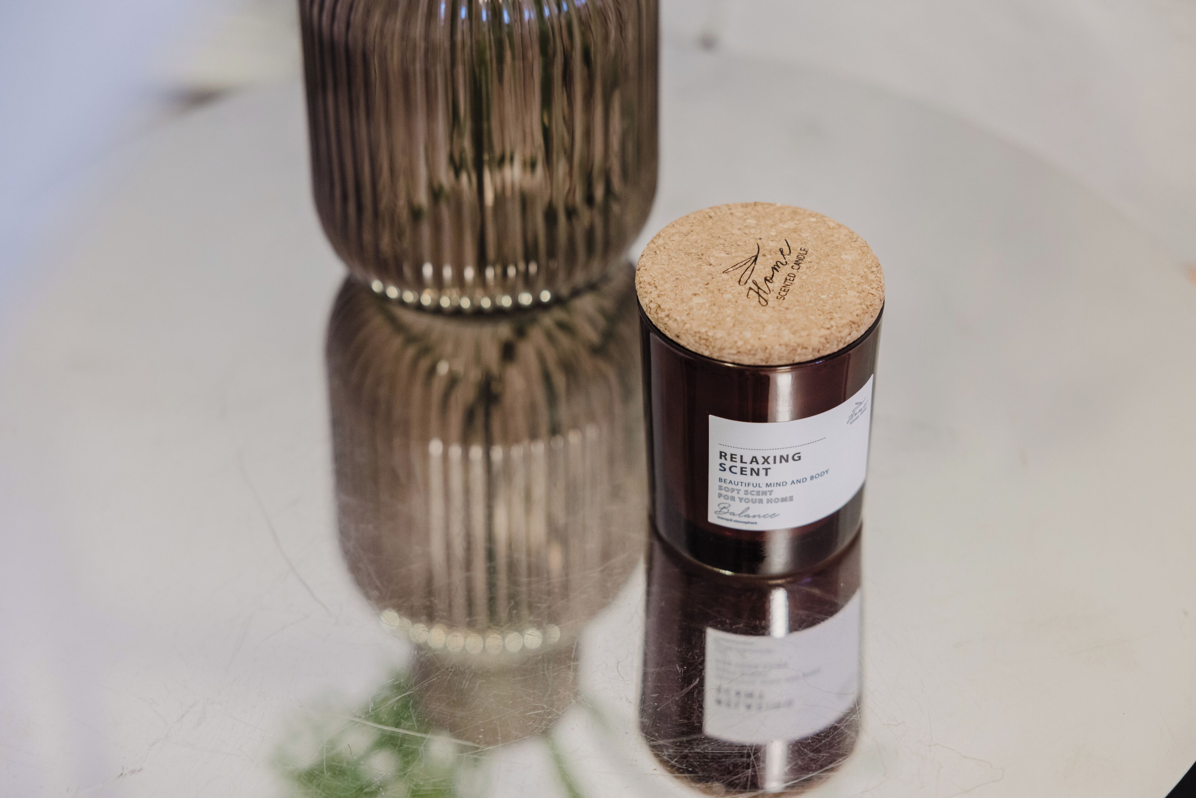 Una botella de aroma relajante con tapón de corcho sobre una superficie reflectante.