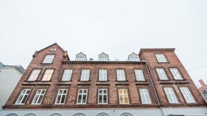 Useista kerroksista koostuva tiilirakennus, jonka julkisivu on symmetrinen, siinä on useita ikkunoita ja keskeinen sisäänkäynti.