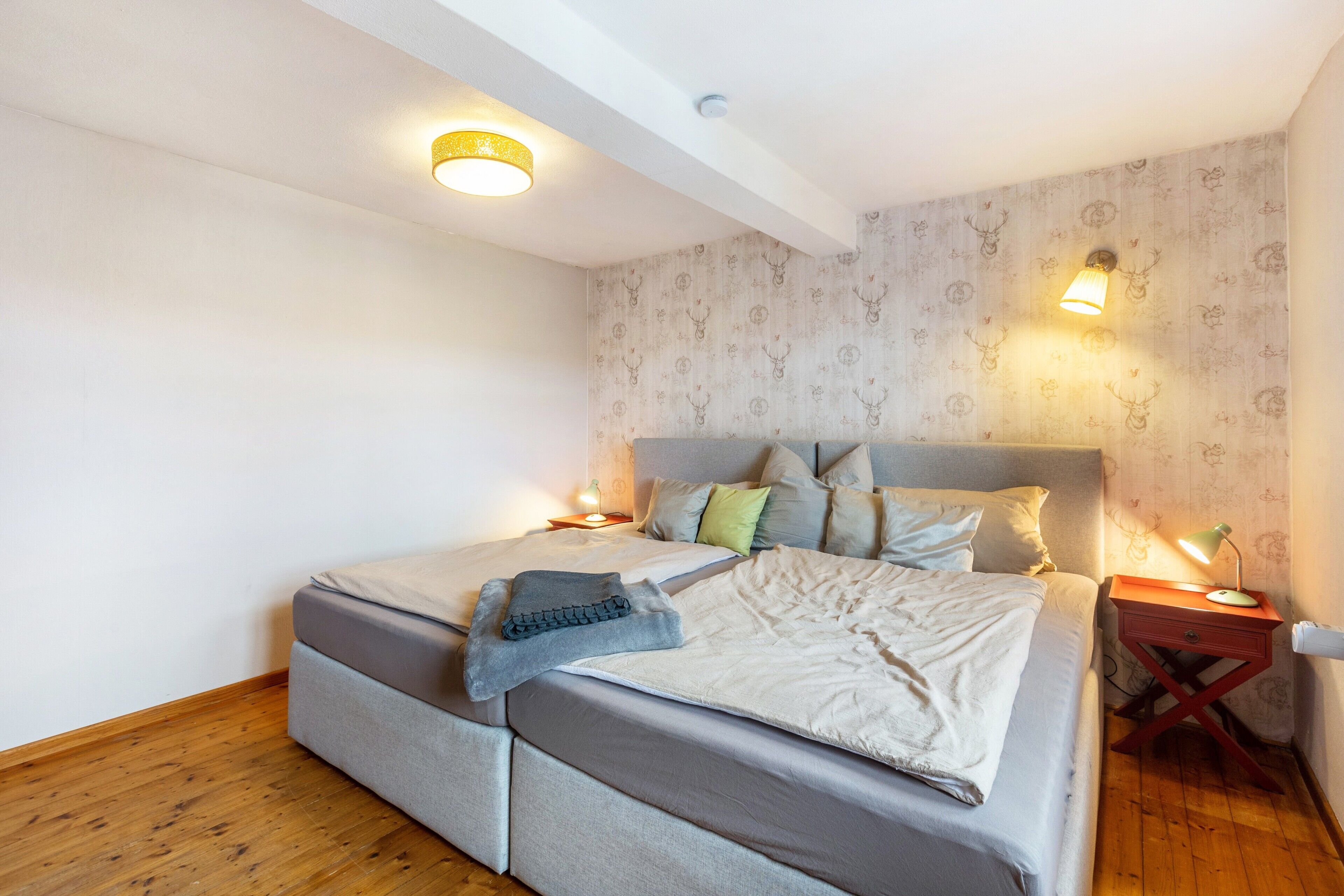 Een slaapkamer met een bed, nachtkastjes en een plafondlamp.