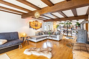 A spacious living room with a wooden ceiling, a sofa, a coffee table, a rug, and a fireplace.