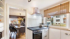 Una cocina compacta con estufa, horno y una ventana con persianas.