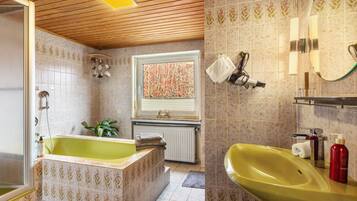 A bathroom with a bathtub, a sink, and a window.