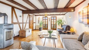 Una sala de estar con chimenea, sofá, mesa de centro y vigas de madera en el techo.