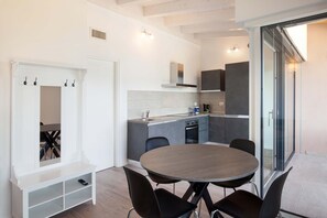 A modern kitchen with a dining area, white walls, and a sliding glass door.
