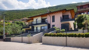 A residential building with a stone facade, multiple balconies, and a staircase leading to the entrance. - Pèler Apartment: Modern Elegance, Stunning Views and Comfort in Brenzone (Castelletto)