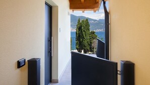 A corridor leading to a balcony with a view of the sea and mountains. - Pèler Apartment: Modern Elegance, Stunning Views and Comfort in Brenzone (Castelletto)