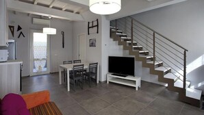 Uma sala de estar moderna com escada, área de jantar e televisão.