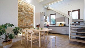 A modern kitchen with a stone wall, wooden dining table, and chairs.