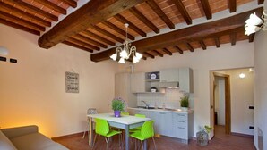 Una cocina amplia con electrodomésticos modernos, un comedor con sillas verdes y un techo de madera.