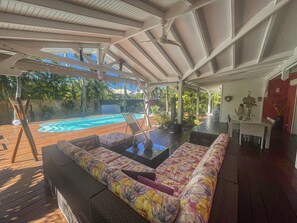 Zona exterior coberta amb piscina, seients per relaxar-se i taula de menjador.