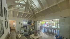 Un salón amplio con techo alto, un sofá, una mesa de centro y vistas al patio exterior.