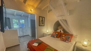 Un dormitorio con cama, mesita de noche, ventana y puerta que da a otra habitación.