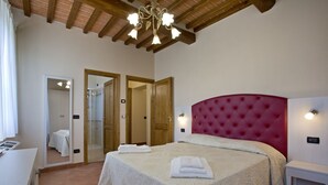 A bedroom with a large bed, a wooden ceiling, and a mirror. - Tenuta San Giovanni - Camomilla Apartment (Lucca)