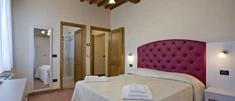 A bedroom with a large bed, a wooden ceiling, and a mirror.