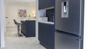 Eine moderne Küche mit dunklen Schränken, einem Edelstahlkühlschrank und einer Barbereich mit Hockern.