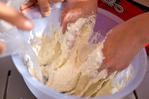 Hands mixing a dough-like substance in a bowl. - Tenuta San Giovanni - Salvia Apartment (Lucca)