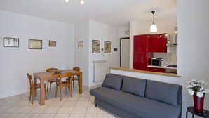 Un soggiorno moderno con tavolo da pranzo, divano e angolo cottura.