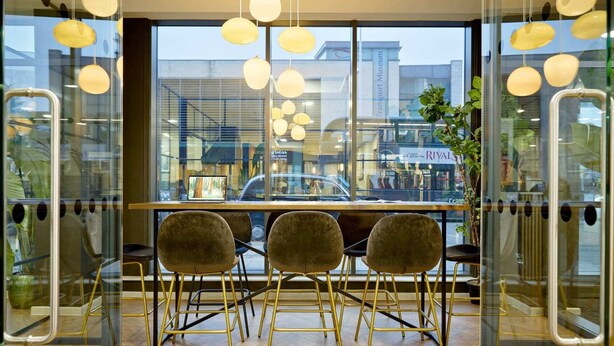 A modern interior with a wooden table and four chairs, large windows, and hanging spherical lights. - For Students Only Ensuites in Coventry (Coventry)