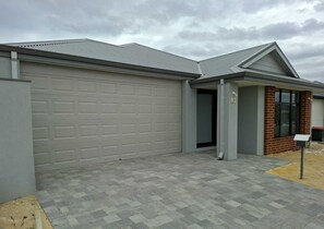 Een modern woongebouw met een grijze garage, een bakstenen entree en een verharde oprit.