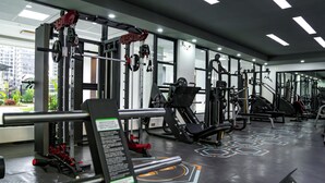 A modern gym with various exercise machines, large windows, and a geometric floor design. - Urban Nest Westlands – Infinity Pool, Gym & Scenic Views close to major malls (Nairobi)