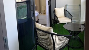A balcony with a view of the city, a small table, two chairs, and a white bedside table with a lamp. - Urban Nest Westlands – Infinity Pool, Gym & Scenic Views close to major malls (Nairobi)
