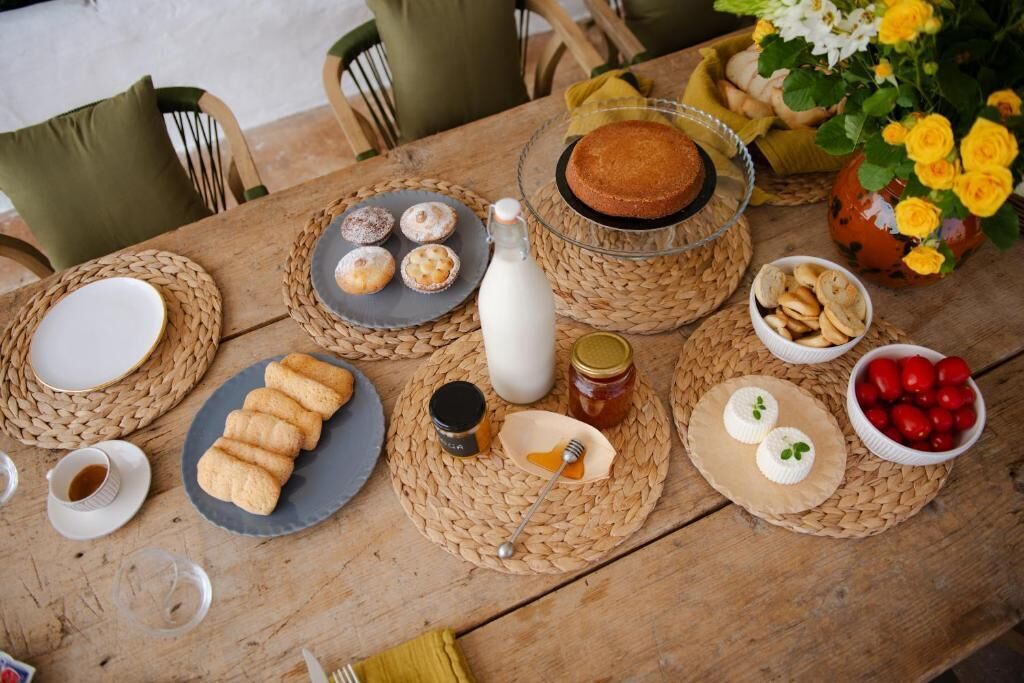 A wooden table with various food items, including pastries, a cake, and a jar of honey.