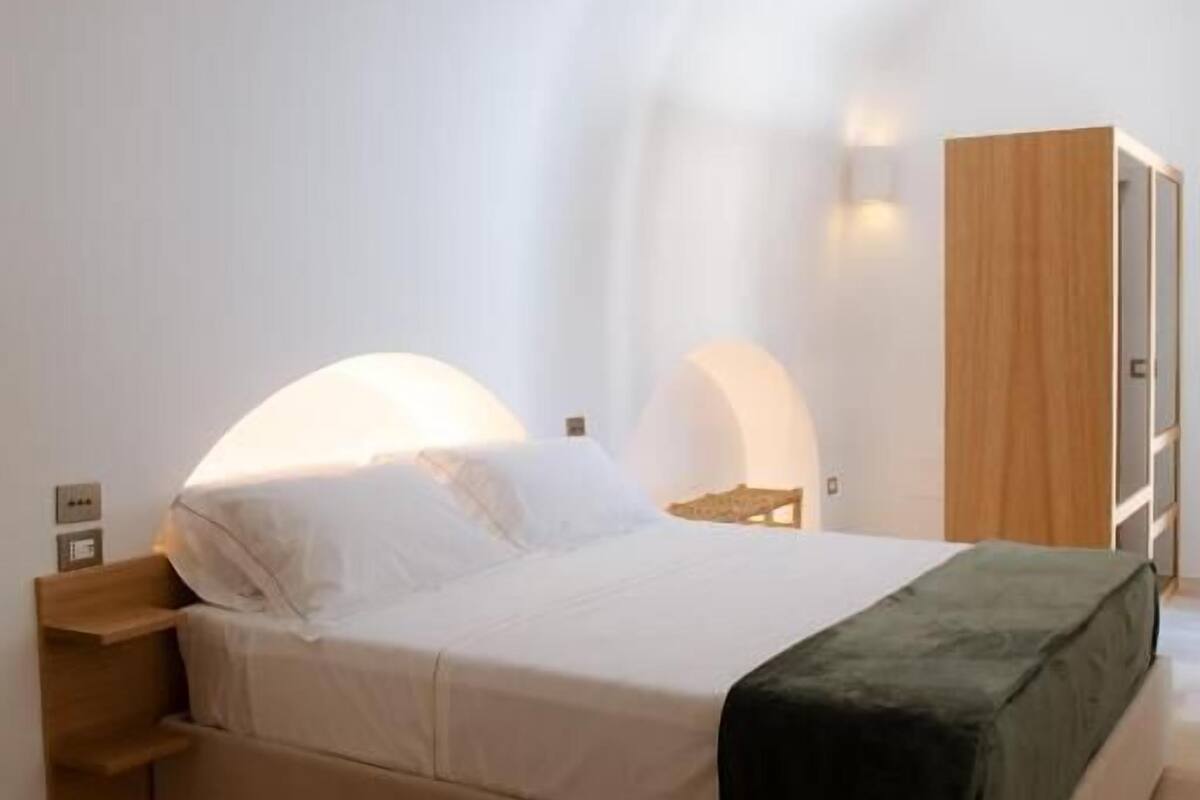 A modern bedroom with a bed, bedside tables, and a wardrobe.