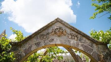 An old stone archway with intricate carvings, surrounded by greenery.