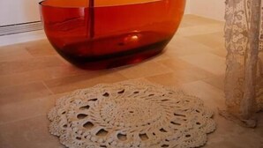 A bathroom with a large, orange vessel sink, a white doily on the floor, and a lace curtain. - Masseria il Pergolo (Martina Franca)