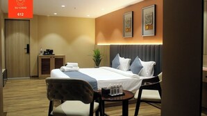 A hotel room with a bed, bedside tables, a desk, and a chair. - The Belita Hotel Bhavnagar (Bhavnagar)