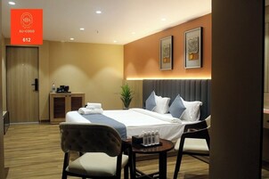 A hotel room with a bed, bedside tables, a desk, and a chair.