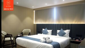 A hotel room with a large bed, two bedside tables, a chair, and a desk. - The Belita Hotel Bhavnagar (Bhavnagar)