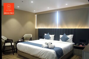 A hotel room with a large bed, two bedside tables, a chair, and a desk.