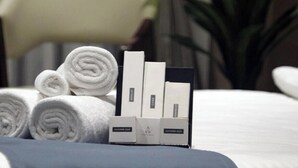 A neatly arranged set of toiletries on a bed, including rolled towels and soap boxes, in a hotel room setting. - The Belita Hotel Bhavnagar (Bhavnagar)