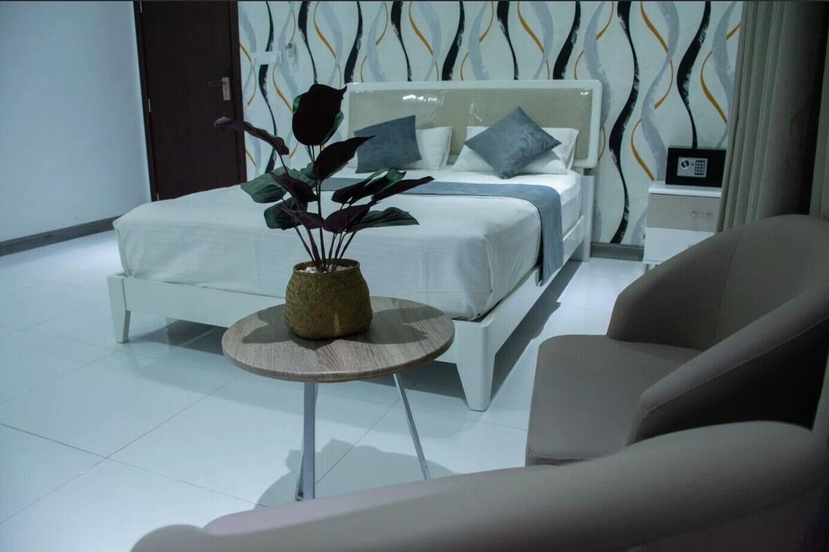 Una camera da letto moderna con un letto, un comodino e una pianta in vaso.